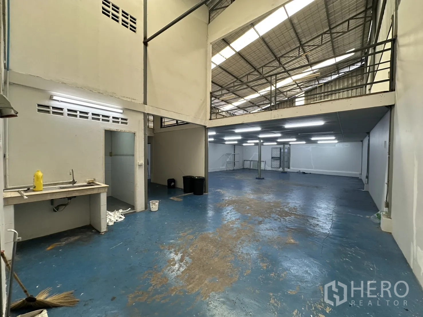 Warehouse for rent in Suan Luang, Bangkok - Utility area with sink, restroom access and high-roof workshop opening to warehouse.