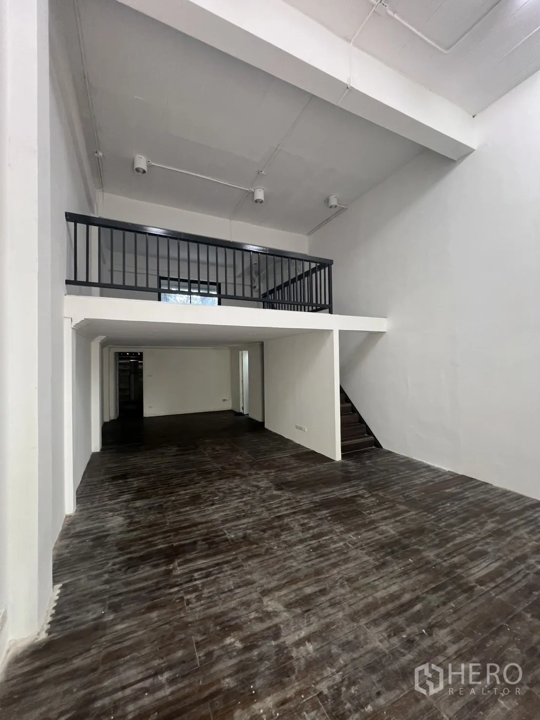 Retail Space for rent in Watthana, Bangkok - Open-plan ground floor with high ceiling, dark wood floors, and mezzanine with staircase.