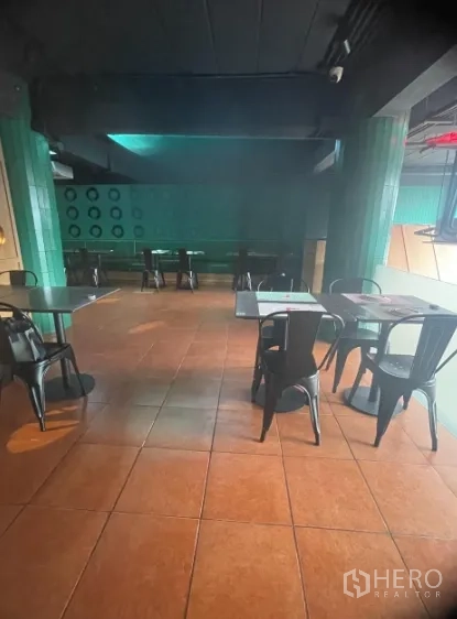 Shophouse for rent in Watthana, Bangkok - Spacious seating zone with terracotta floor tiles and green columns.