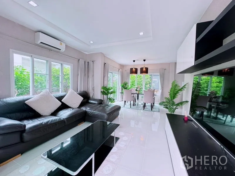 Detached House for rent in Prawet, Bangkok - Open-plan living and dining area with garden views and glossy white floor.