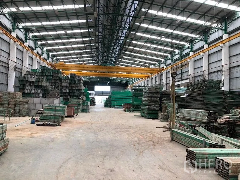 Factory for rent or sale in Lat Lum Kaeo, Pathum Thani - Long warehouse aisle with multiple gantry cranes and neatly stacked materials.