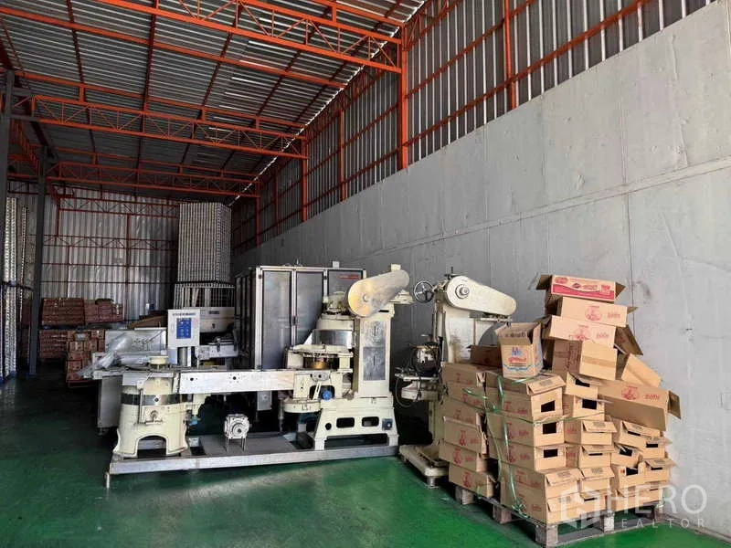 Factory for sale in Samut Prakan - Warehouse zone with canning machines and piles of packaging cartons.