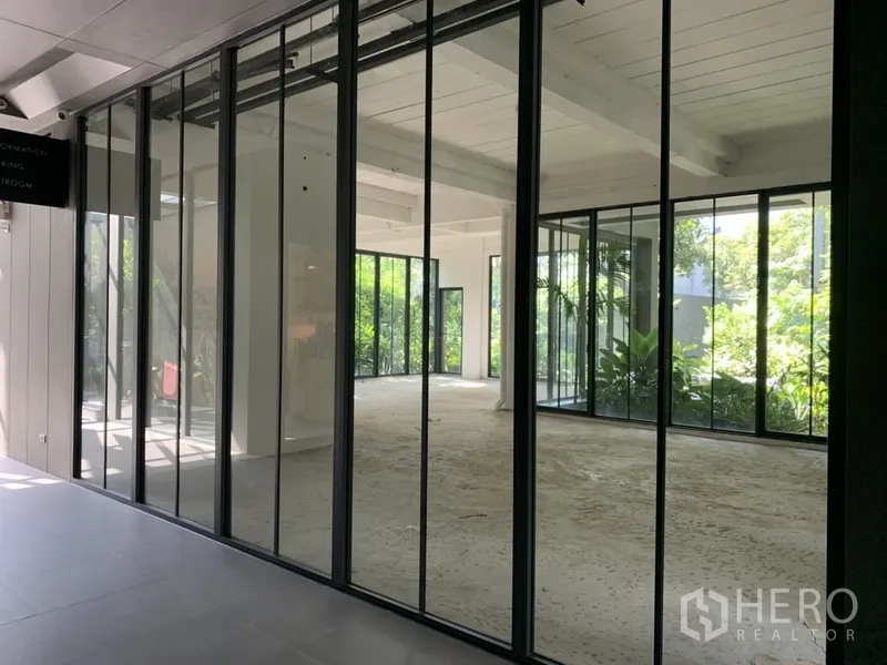 办公空间 出租在Khlong Toei, Bangkok - 大面积玻璃移门展示通透明亮的办公空间与绿意