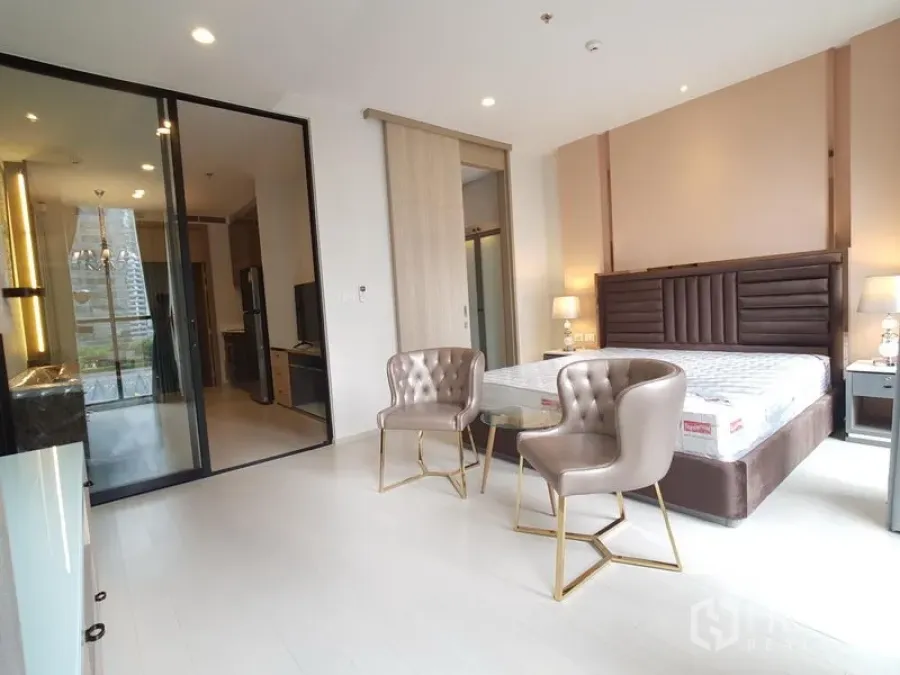 Condominium for rent in Pathum Wan, Bangkok - Spacious bedroom with king bed, upholstered headboard, two chairs and large windows.