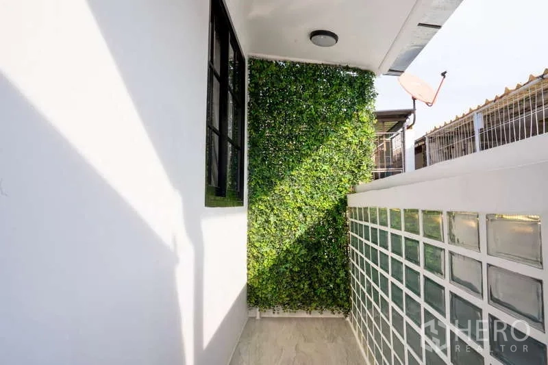 Townhouse for rent in Khlong Toei, Bangkok - Side balcony featuring a glass-block wall and green vertical garden.