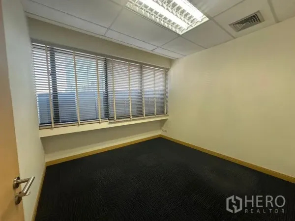 Office Space for rent in Bang Na, Bangkok - Empty office room with a long row of windows fitted with venetian blinds.