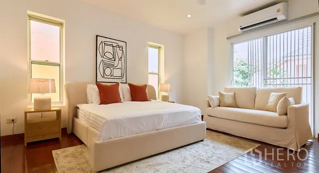 Detached House for rent in Watthana, Bangkok - Primary bedroom with king bed, sofa and natural light from tall windows.