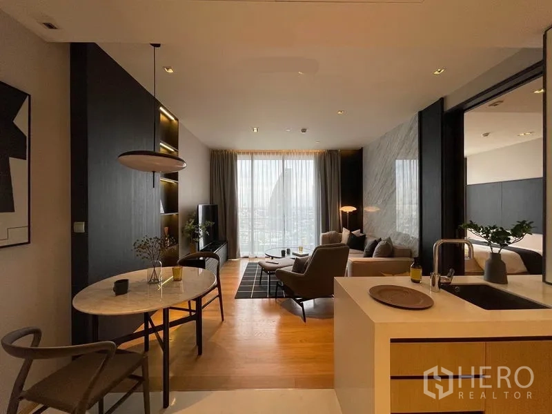 Condominium for rent in Khlong Toei, Bangkok - Contemporary open-plan living room with floor-to-ceiling window, dining table and kitchenette overlooking the city.