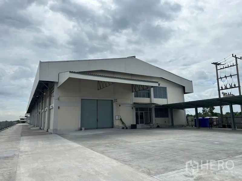 Factory for rent in Lam Luk Ka, Pathum Thani - Modern factory exterior with wide loading bay, double sliding doors and large concrete yard.