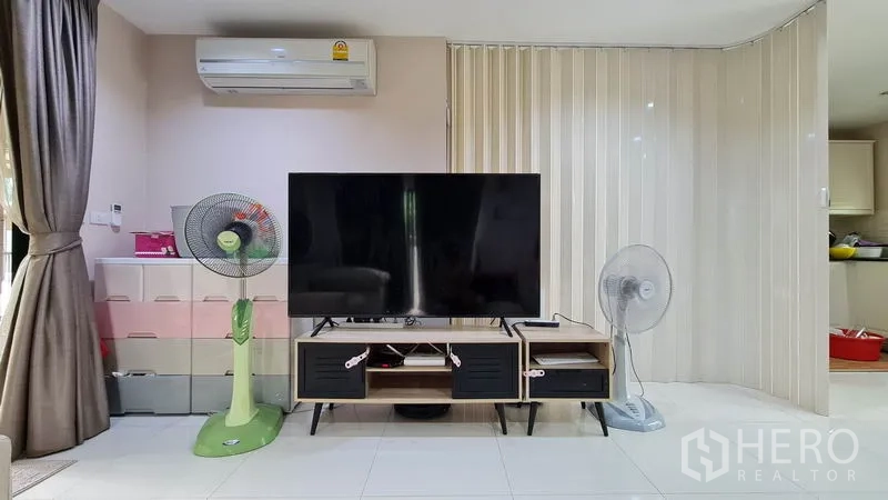 Detached House for sale in Samut Prakan - Living area media wall with large TV, console and air conditioner.