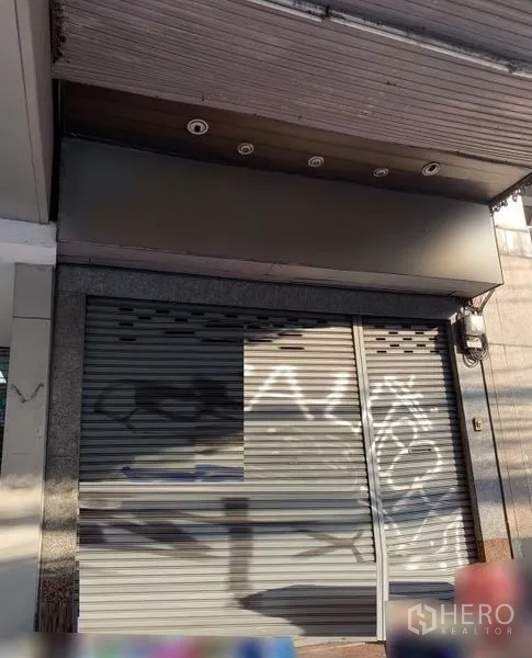 Shophouse for rent in Bang Rak, Bangkok - Street-facing shophouse exterior with closed metal roller shutter, canopy, and recessed lights in Bang Rak.