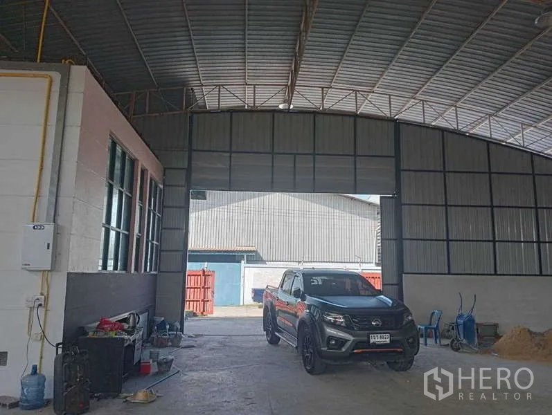 Warehouse for rent in Lam Luk Ka, Pathum Thani - Covered loading bay inside the warehouse with tall door opening and parking space for trucks.