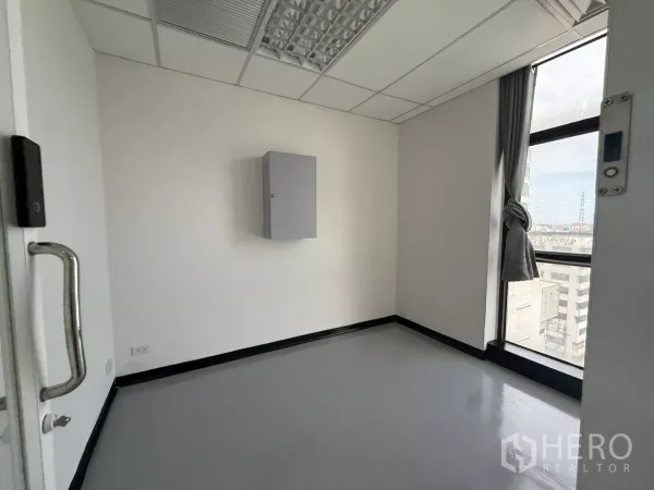Office Space for rent - Compact private office with large window and city view, white walls and vinyl flooring.