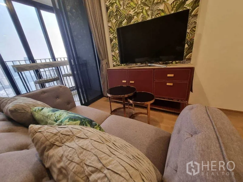 Condominium for rent in Bang Rak, Bangkok - TV console against botanical wallpaper beside sliding door to balcony.