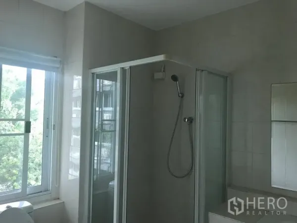 Home Office for rent or sale in Watthana, Bangkok - Bright bathroom featuring a glass-enclosed shower and a large sliding window.