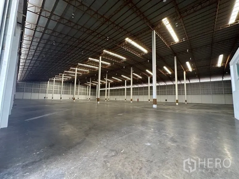 Warehouse for rent in Phra Nakhon Si Ayutthaya - Vast high-bay warehouse interior with concrete floor, skylights and white support columns.