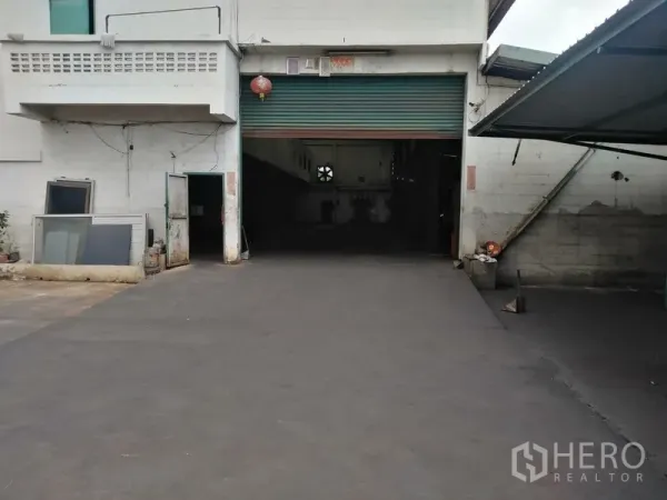 Factory for rent in Saphan Sung, Bangkok - Main roller shutter entrance with wide driveway leading to the production hall.