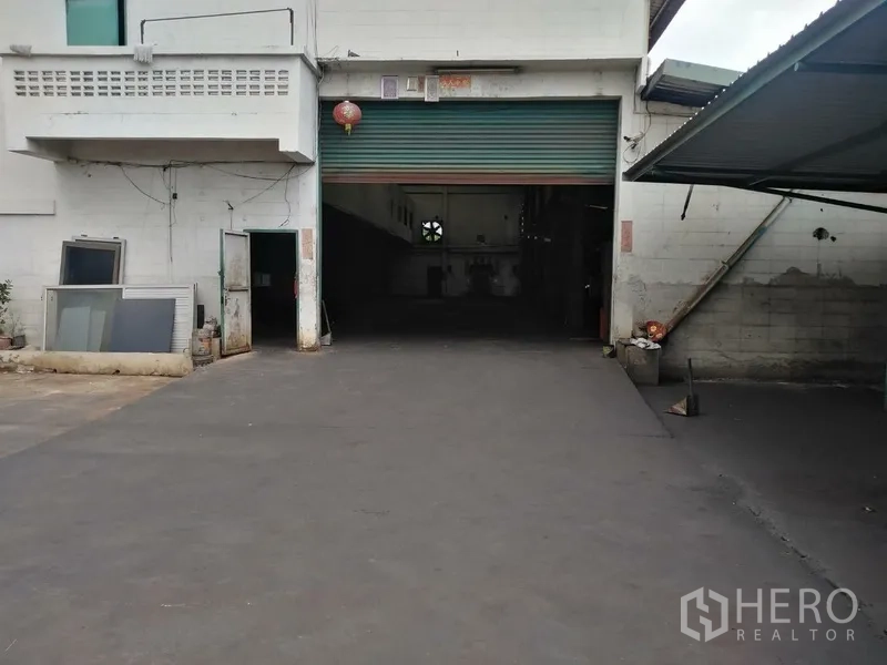 Factory for rent in Saphan Sung, Bangkok - Main roller shutter entrance with wide driveway leading to the production hall.