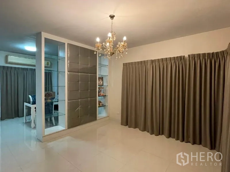 Detached House for sale in Khlong Toei, Bangkok - Second lounge with chandelier, partition shelving and full-length curtains.