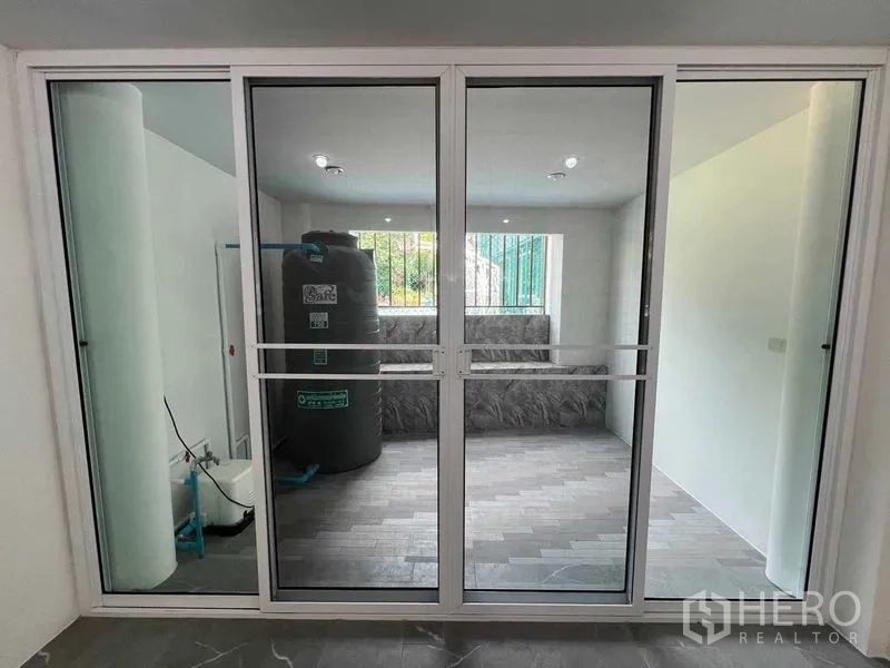 Townhouse for rent in Khlong Toei, Bangkok - Sliding glass doors opening to the utility terrace with water tank.