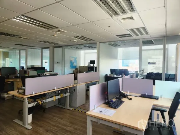 Office Space for rent in Watthana, Bangkok - Rows of desks with monitors beside glass-partitioned rooms in a modern Bangkok office.