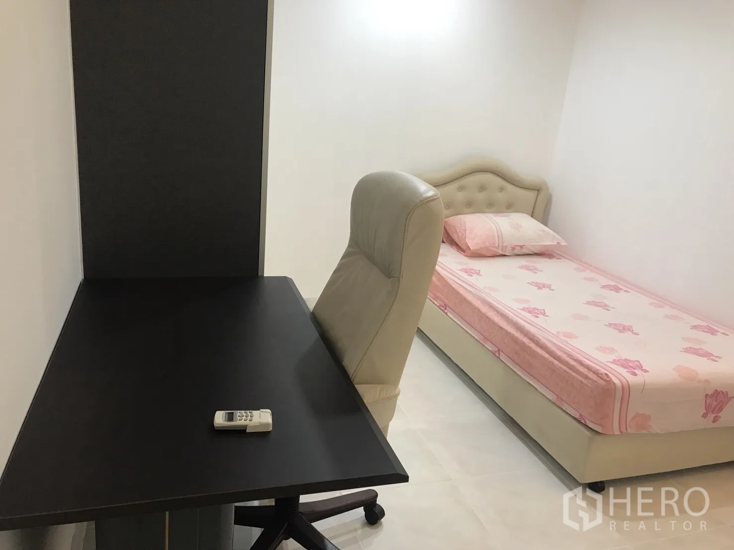 Condominium for rent in Khlong Toei, Bangkok - Compact bedroom with single bed in pink bedding, study desk, and office chair.