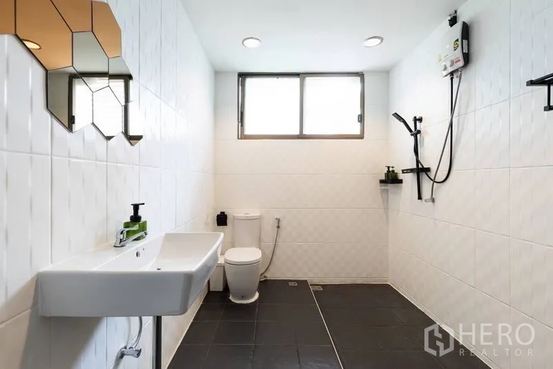 Townhouse for rent in Watthana, Bangkok - Large bathroom with walk-in shower, white tiles and black floor.
