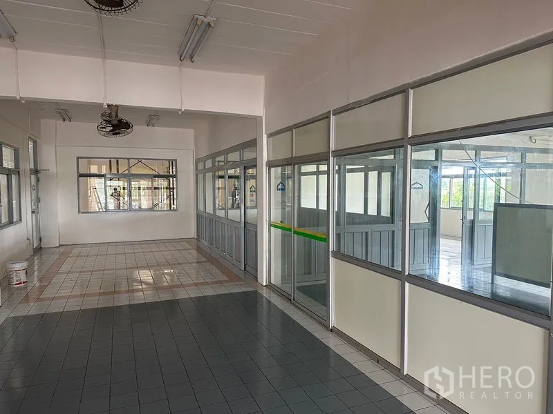 Factory for rent in Lam Luk Ka, Pathum Thani - Interior corridor with glass-partitioned offices and tiled floors inside the factory building.