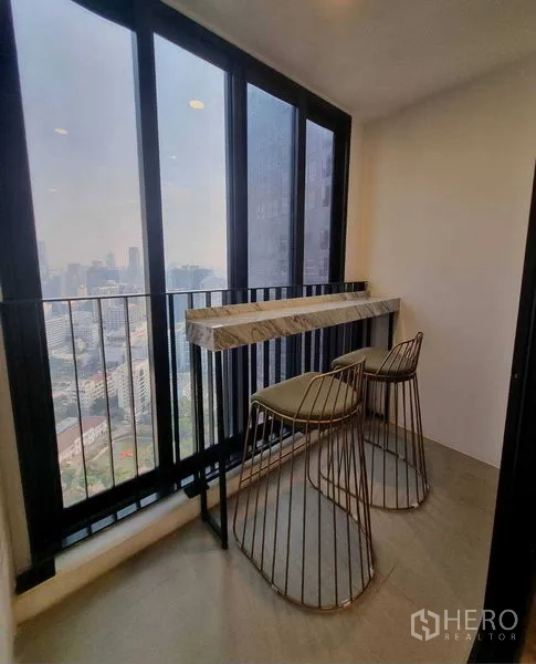 Condominium for rent in Bang Rak, Bangkok - Enclosed balcony with marble bar counter, two high stools and skyline view.