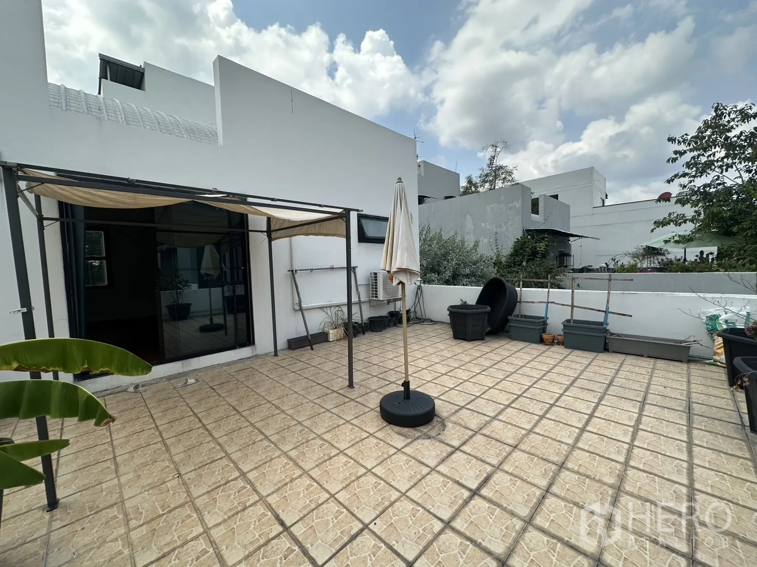 Detached House for rent in Watthana, Bangkok - Spacious tiled rooftop terrace with awning and garden planters.