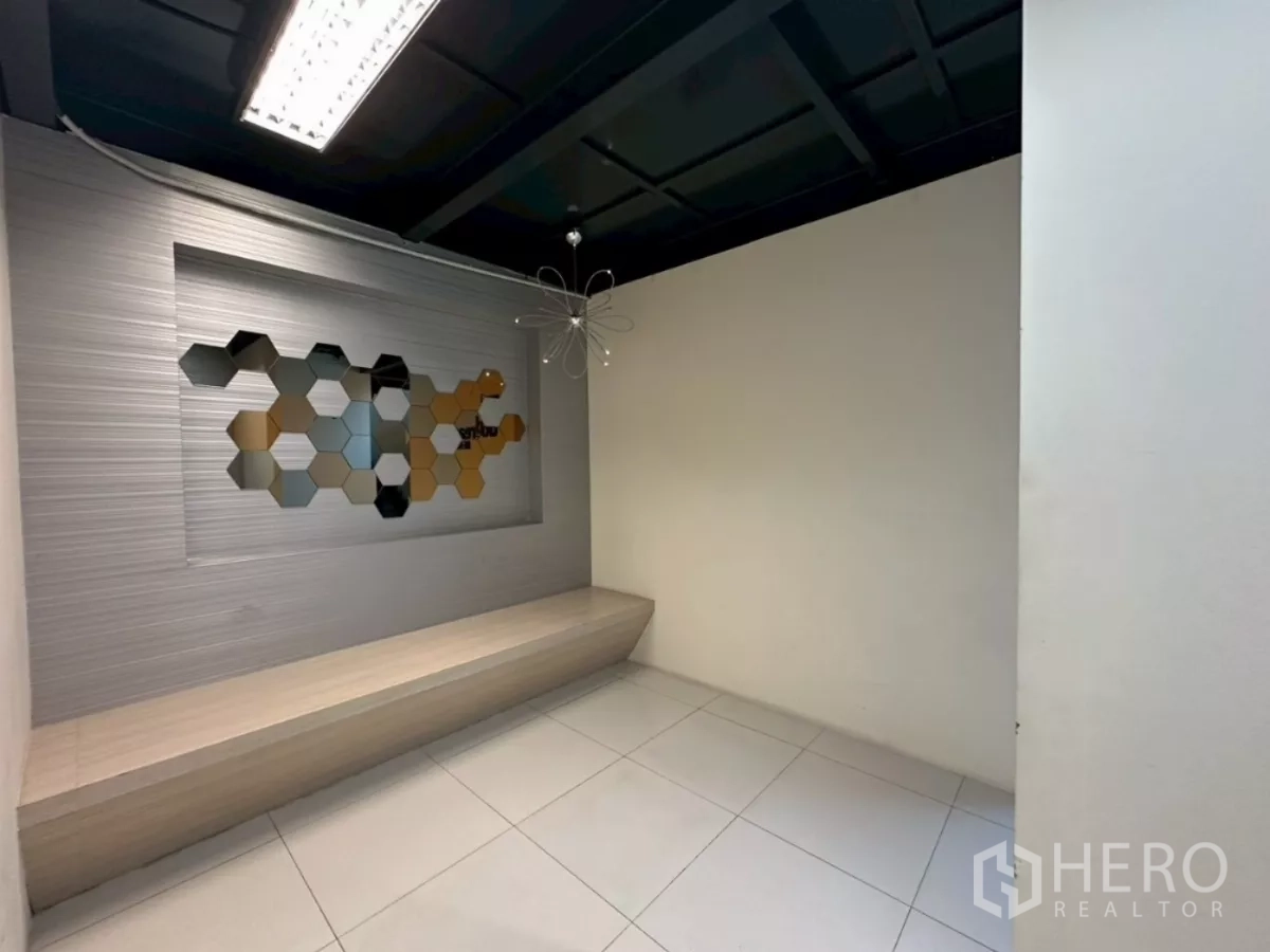 Office Space for rent in Khlong Toei, Bangkok - Reception nook with a built-in bench and honeycomb wall decor under a modern light.