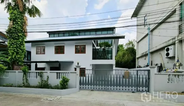 Home Office for rent in Lat Phrao, Bangkok - Renovated two‑storey home office with white facade, clerestory windows and sliding metal gate on a quiet street.