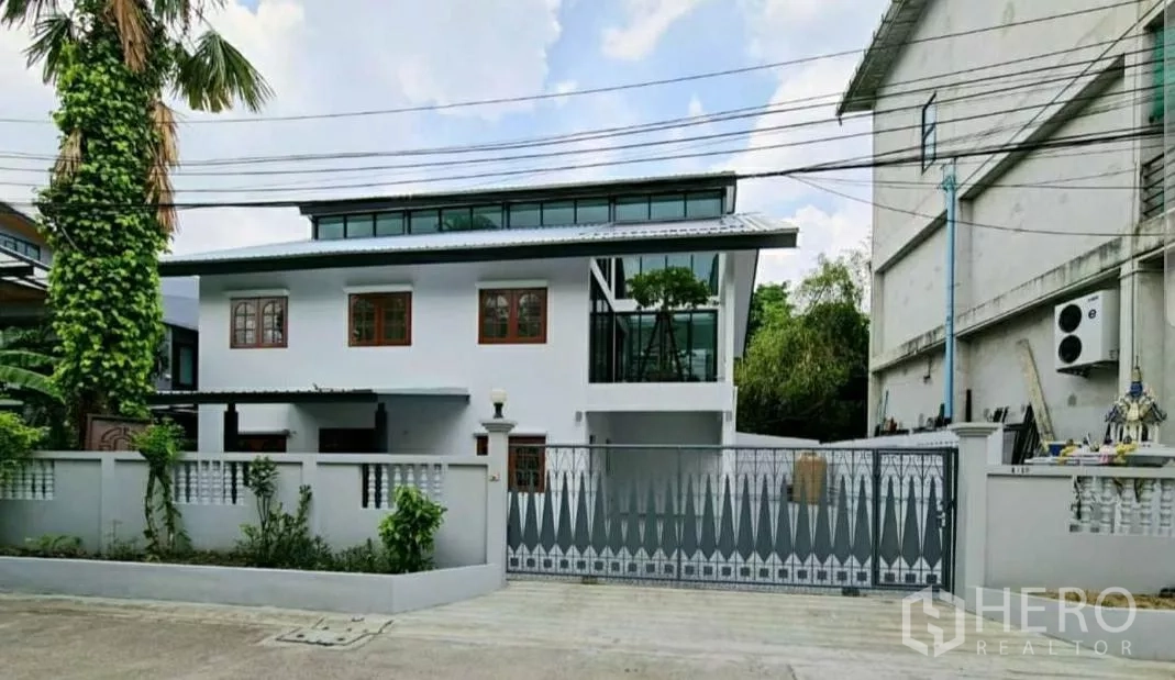 Home Office for rent in Lat Phrao, Bangkok - Renovated two‑storey home office with white facade, clerestory windows and sliding metal gate on a quiet street.