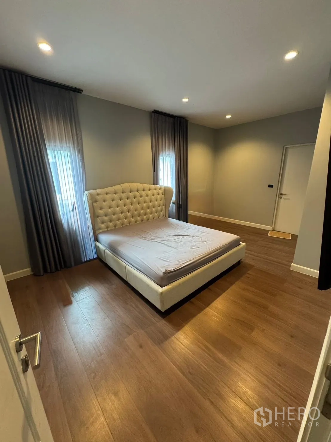 Detached House for sale in Mueang Pathum Thani, Pathum Thani - Bedroom with upholstered headboard, recessed lights and wood floors.