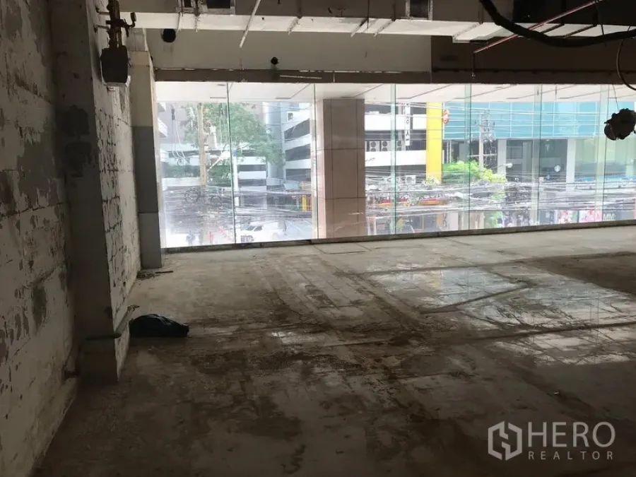Retail Space for rent in Watthana, Bangkok - Unfurnished retail shell with floor-to-ceiling glass frontage overlooking a city street, exposed ceiling and concrete floor in Watthana, Bangkok.