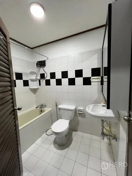 Townhouse for rent in Din Daeng, Bangkok - Bathroom with bathtub, water heater, toilet and black-and-white wall tiles.