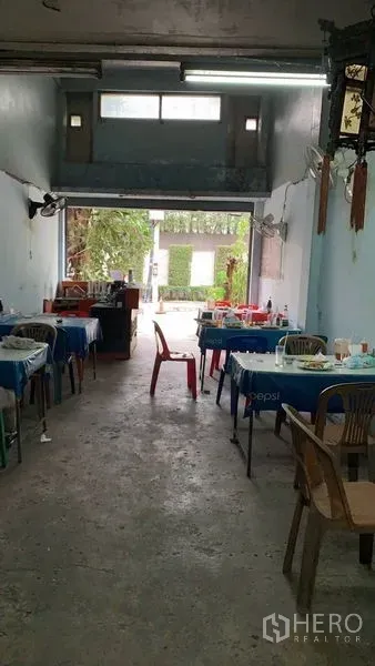 Shophouse for sale in Khlong Toei, Bangkok - Long shop hall opening to the street with concrete floor and natural light at the entrance.
