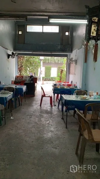 Shophouse for sale in Khlong Toei, Bangkok - Long shop hall opening to the street with concrete floor and natural light at the entrance.