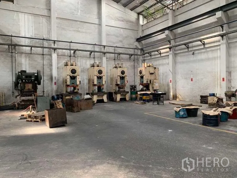 Factory for rent in Samut Prakan - Row of heavy stamping machines lined along a tall-walled industrial bay.