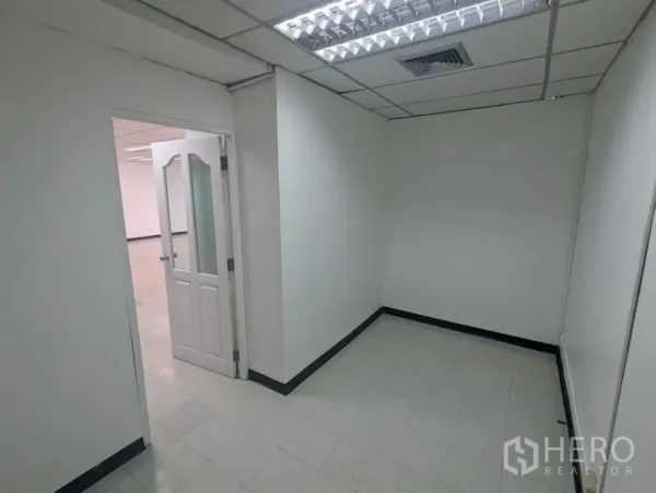 Office Space for rent or sale - Compact private office room with white walls, tile flooring and a glass-panel door under fluorescent lighting.