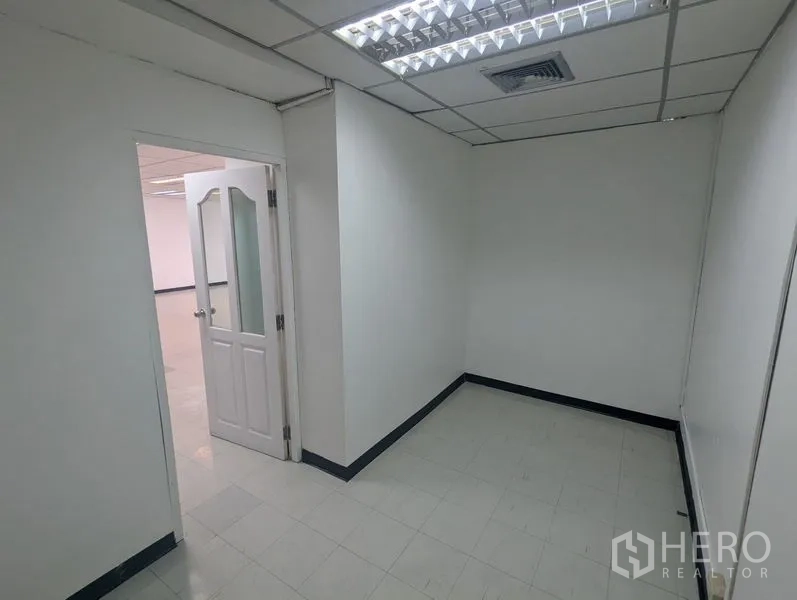 Office Space for rent or sale - Compact private office room with white walls, tile flooring and a glass-panel door under fluorescent lighting.