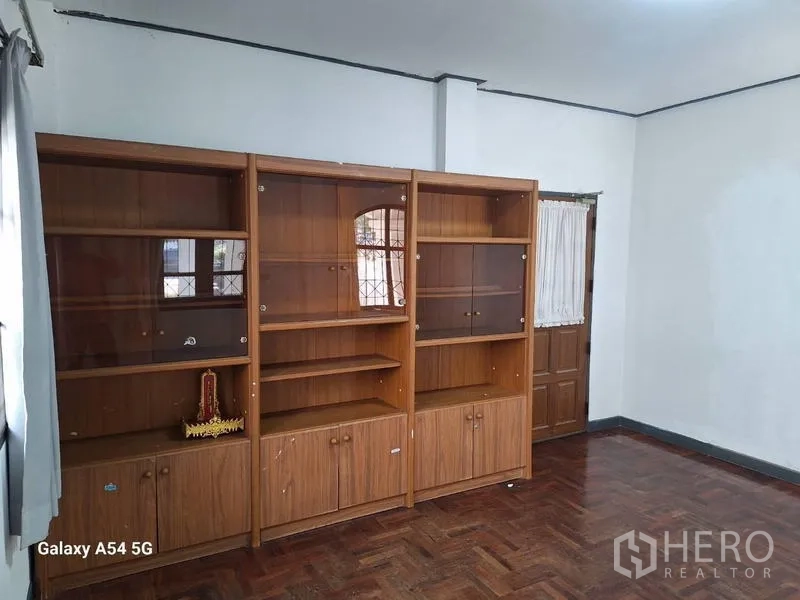 Detached House for rent in Bang Na, Bangkok - Empty living room featuring built-in wooden shelving and parquet flooring.
