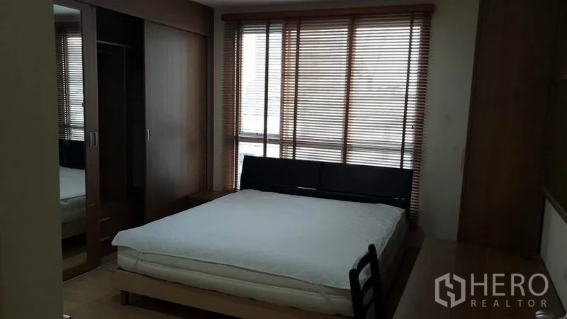 Condominium for rent in Bang Rak, Bangkok - Bedroom with queen bed, floor-to-ceiling windows with blinds, and a built-in mirrored wardrobe.