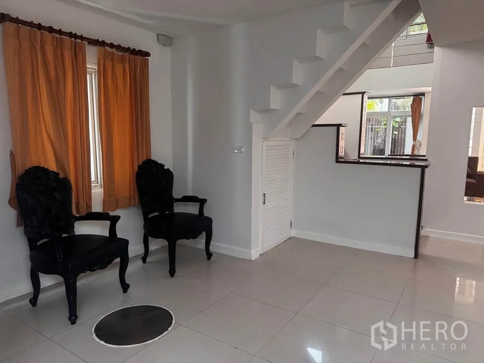 Townhouse for rent in Huai Khwang, Bangkok - Entry nook under the stairs with two accent chairs and a window.
