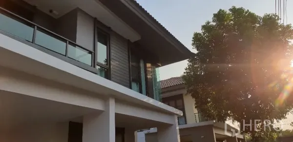Detached House for rent or sale in Lam Luk Ka, Pathum Thani - Close-up of upper facade with glass railing and afternoon sunlight.