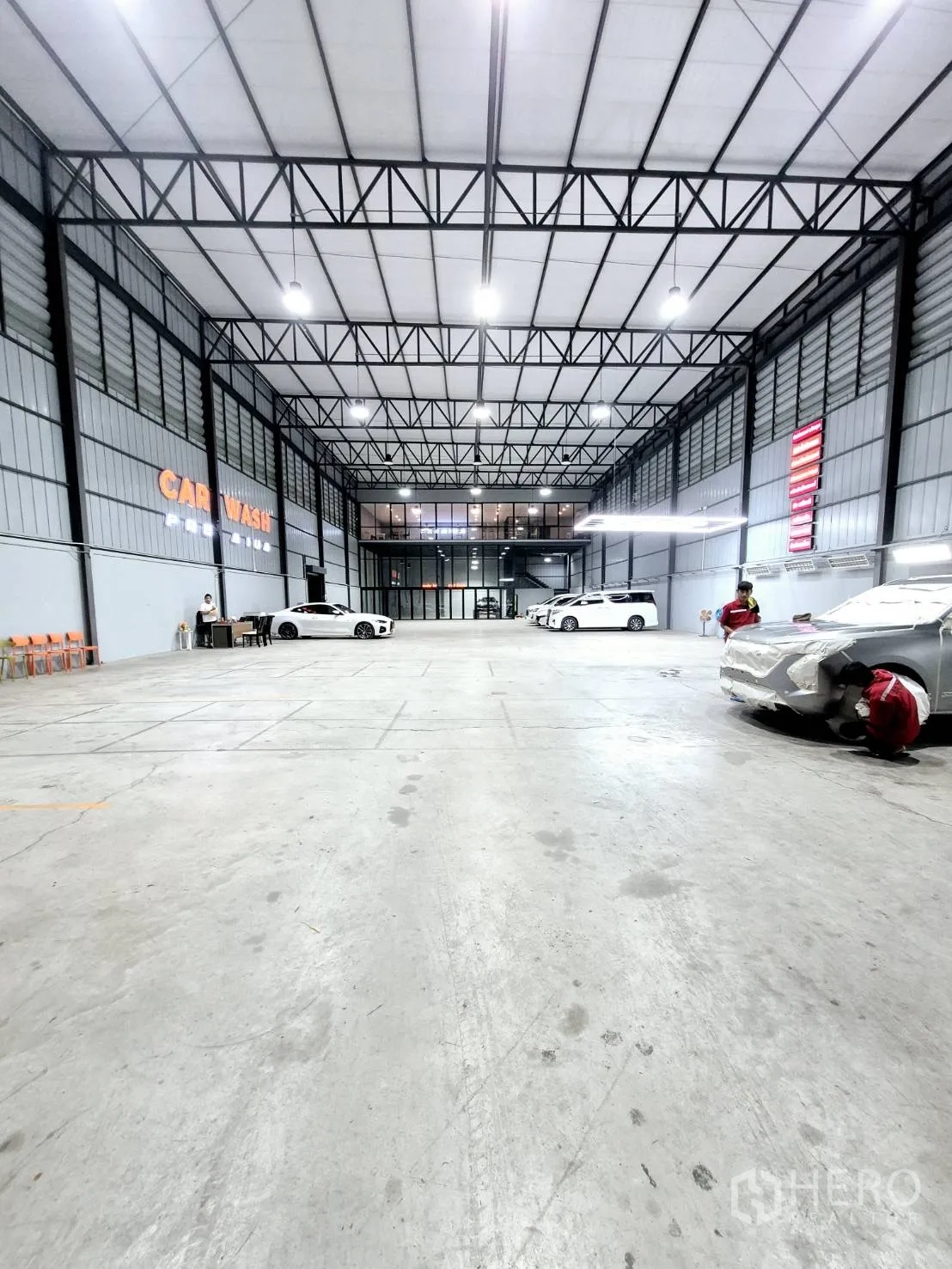 Warehouse for rent in Sai Mai, Bangkok - Large open warehouse floor with truss ceiling, bright lighting, and a car wash bay.