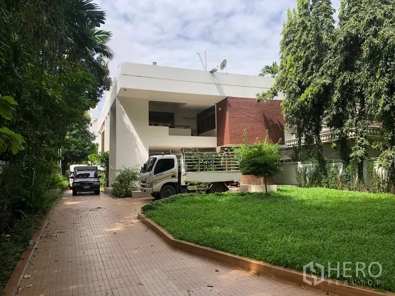 Detached House for rent in Watthana, Bangkok - Modern detached house exterior with long driveway and lawn in Watthana, Bangkok.