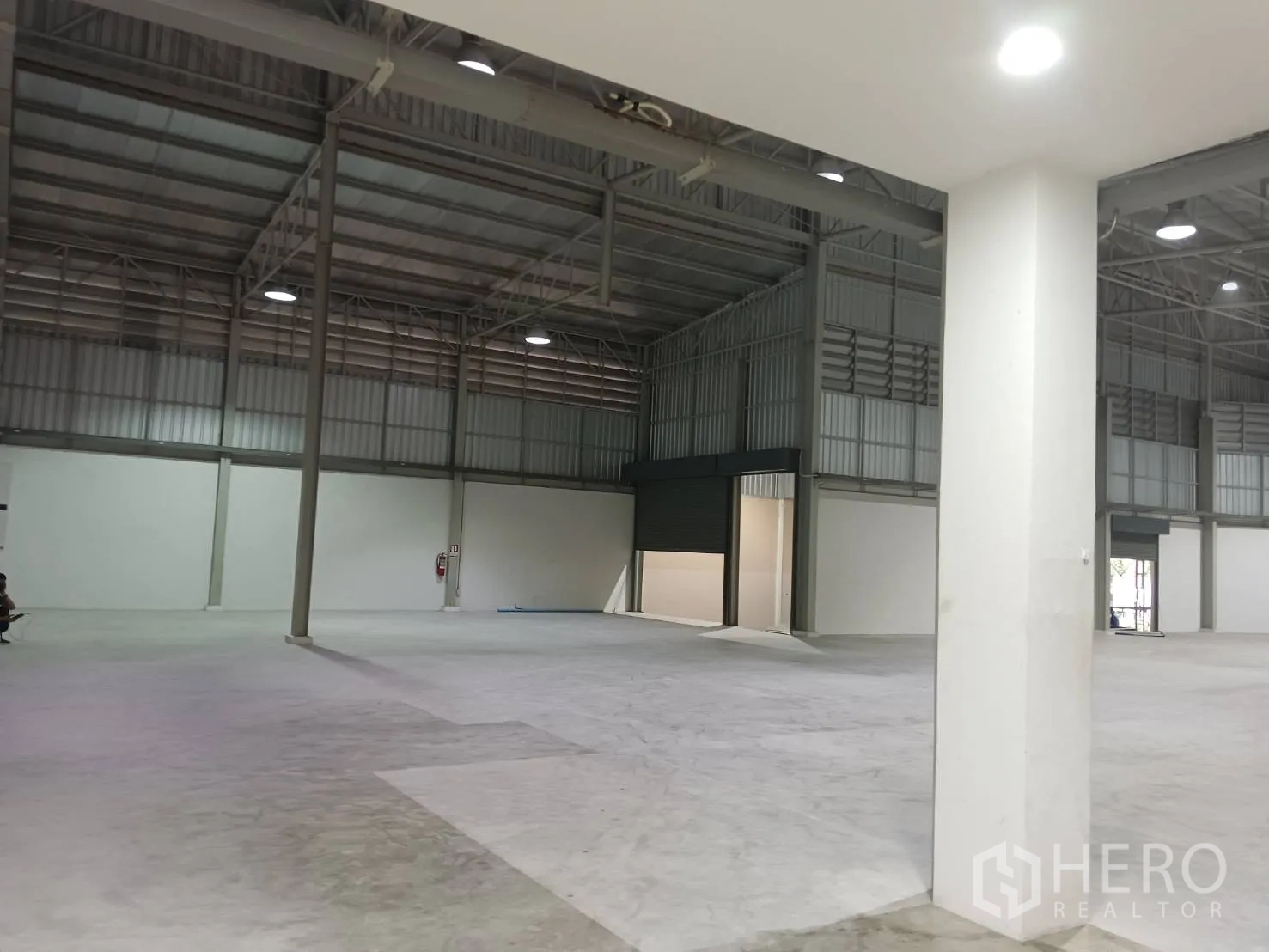 货栈 出租在Khlong Sam Wa, Bangkok - 开放式仓库地面，立柱、卷闸门与工业照明。
