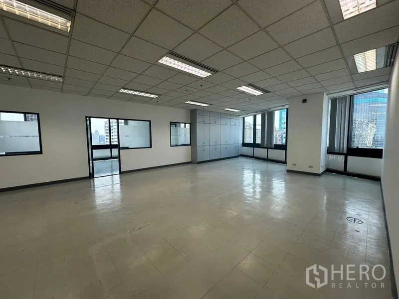 Office Space for rent in Khlong Toei, Bangkok - Spacious open-plan office with grid ceiling lights, windows, and built-in storage cabinets.