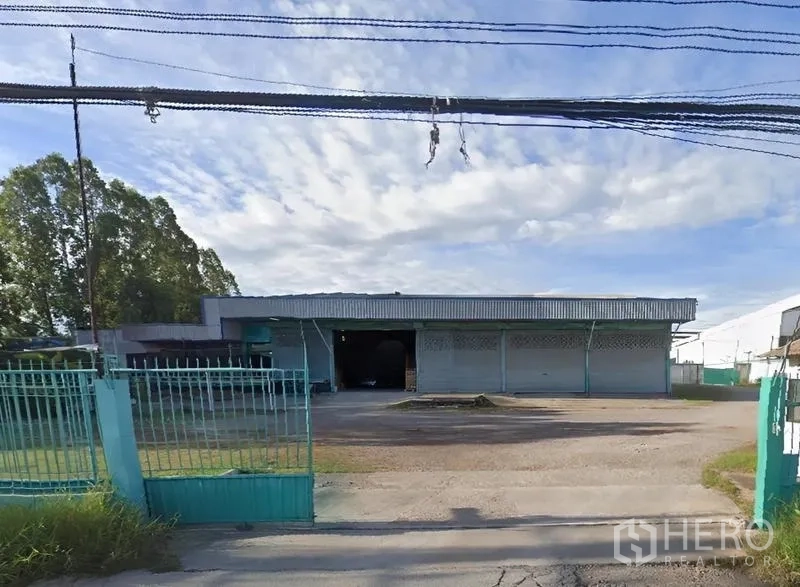 Warehouse for rent in Mueang Samut Sakhon, Samut Sakhon - Street view of a gated warehouse with a wide forecourt and teal fence in Mueang Samut Sakhon.